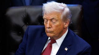 Donald Trump looks down while sitting at his desk in the Oval Office