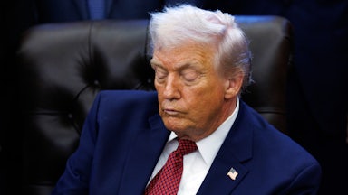 Donald Trump looks down while sitting at his desk in the Oval Office