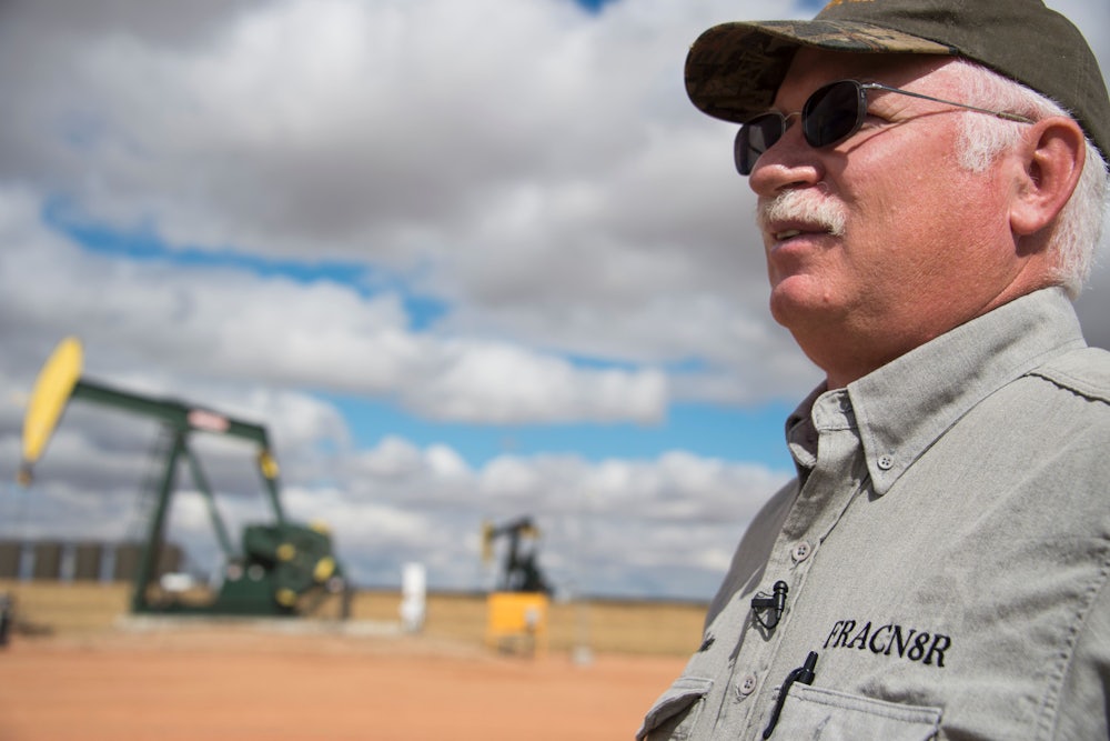 An oil industry consultant talks in front of a drilling rig.