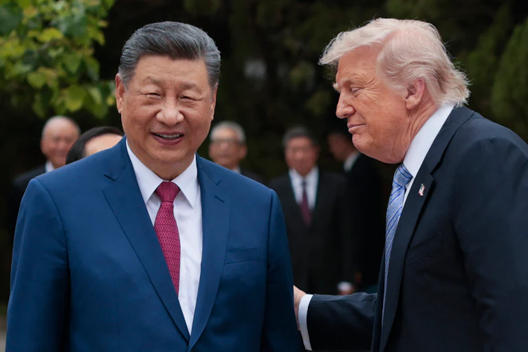Chinese President Xi Jinping smiles while standing next to Donald Trump, who puts his hand on Xi's arm