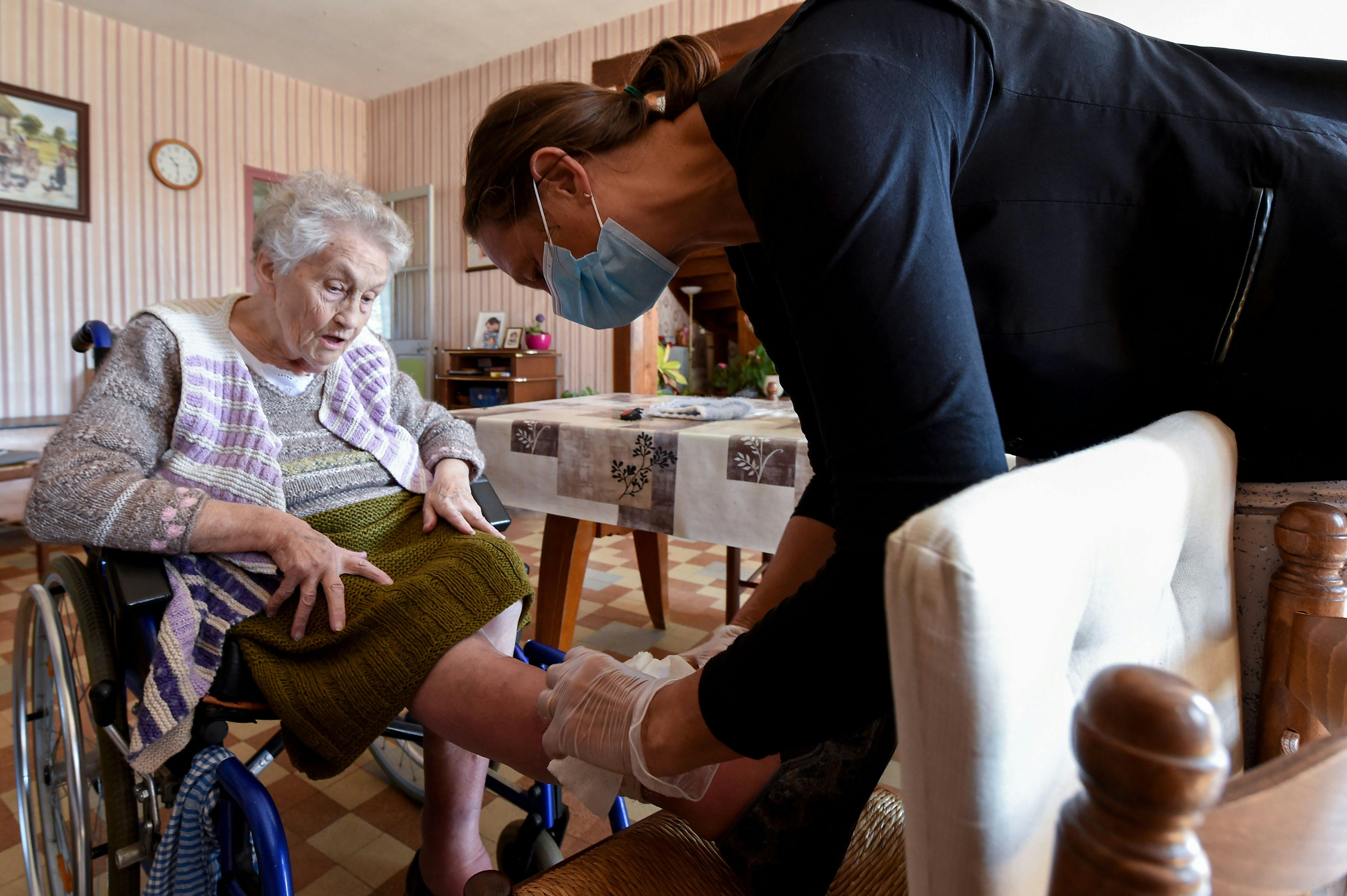 A nurse examines a woman's leg.