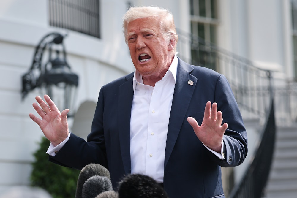 Donald Trump holds up his hands while speaking to reporters outside the White House