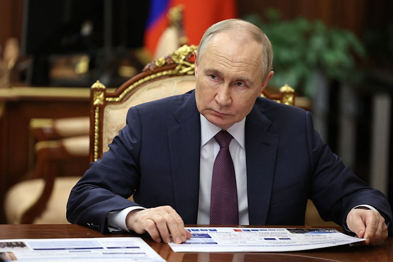 Russian President Vladimir Putin sits at a desk