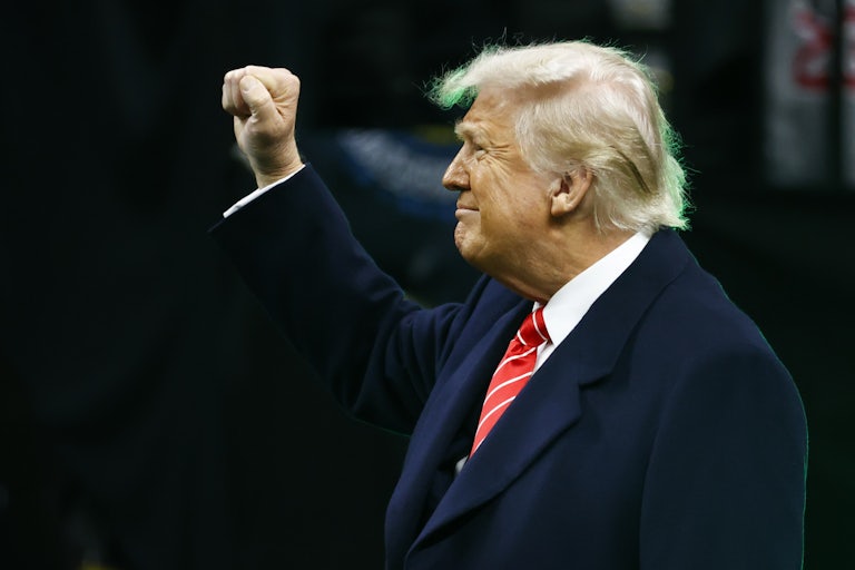 Donald Trump raises his fist as he enters a stadium in Philadelphia for a college wrestling tournament