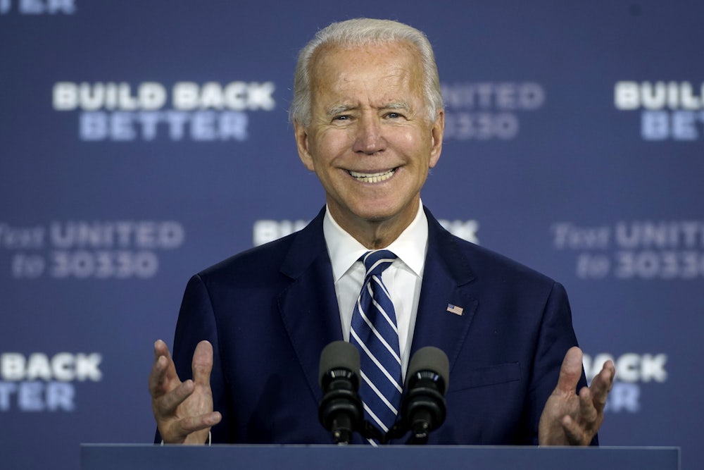 A close-up of a smiling Joe Biden standing behind a lectern.