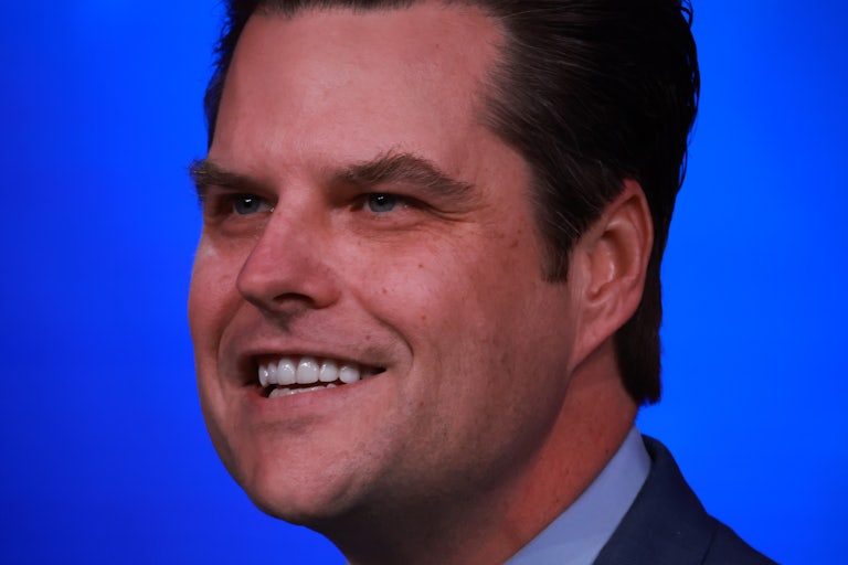 close-up of Matt Gaetz smiling with blue background (looks a bit like a creepy yearbook photo)