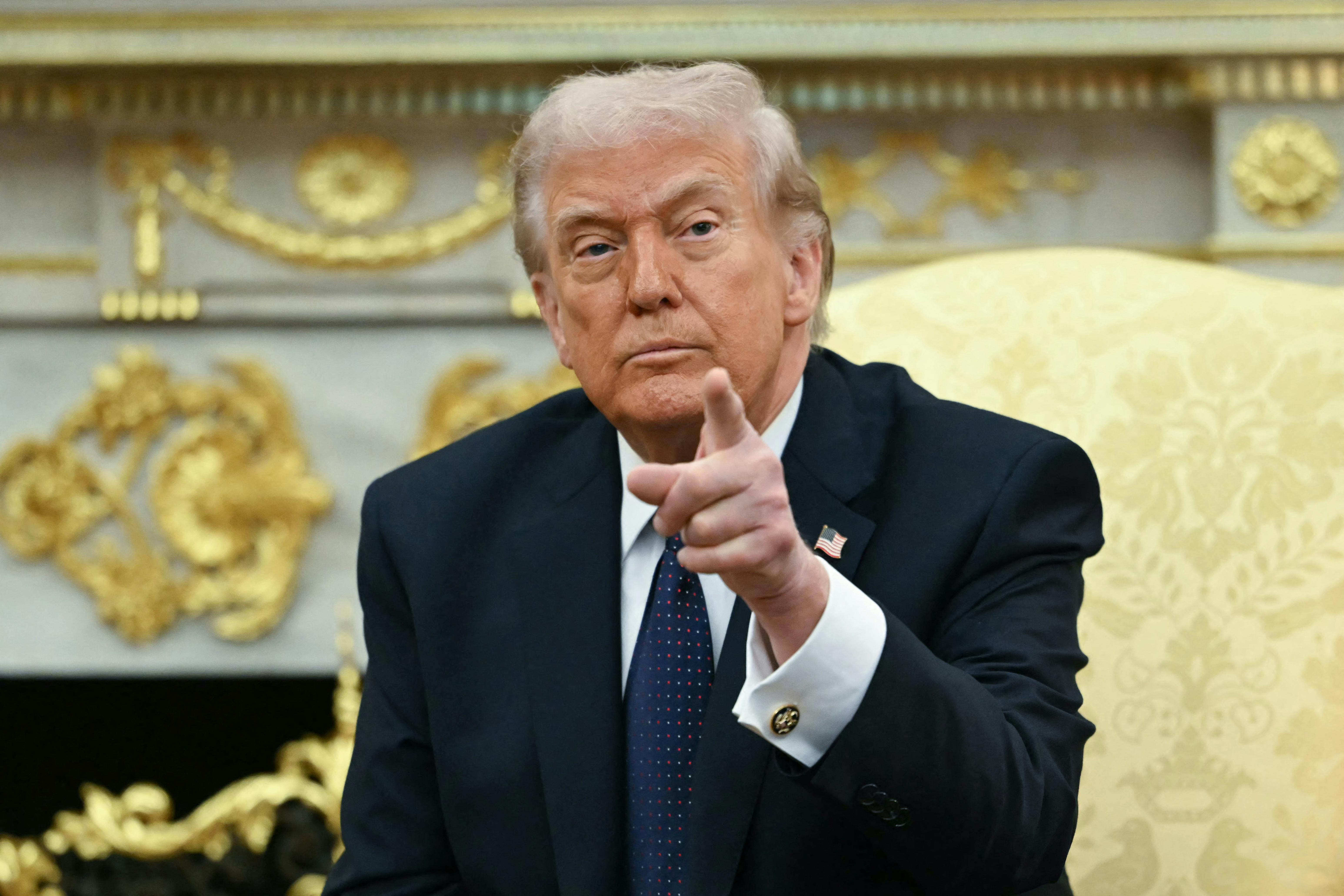 President Donald Trump points while sitting in the Oval Office of the White House.