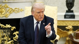 Donald Trump points while sitting the Oval Office of the White House.