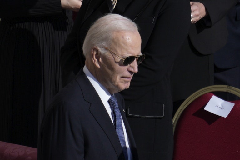 Joe Biden wears sunglasses and looks down while walking at Pope Francis's funeral