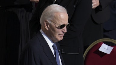 Joe Biden wears sunglasses and looks down while walking at Pope Francis's funeral
