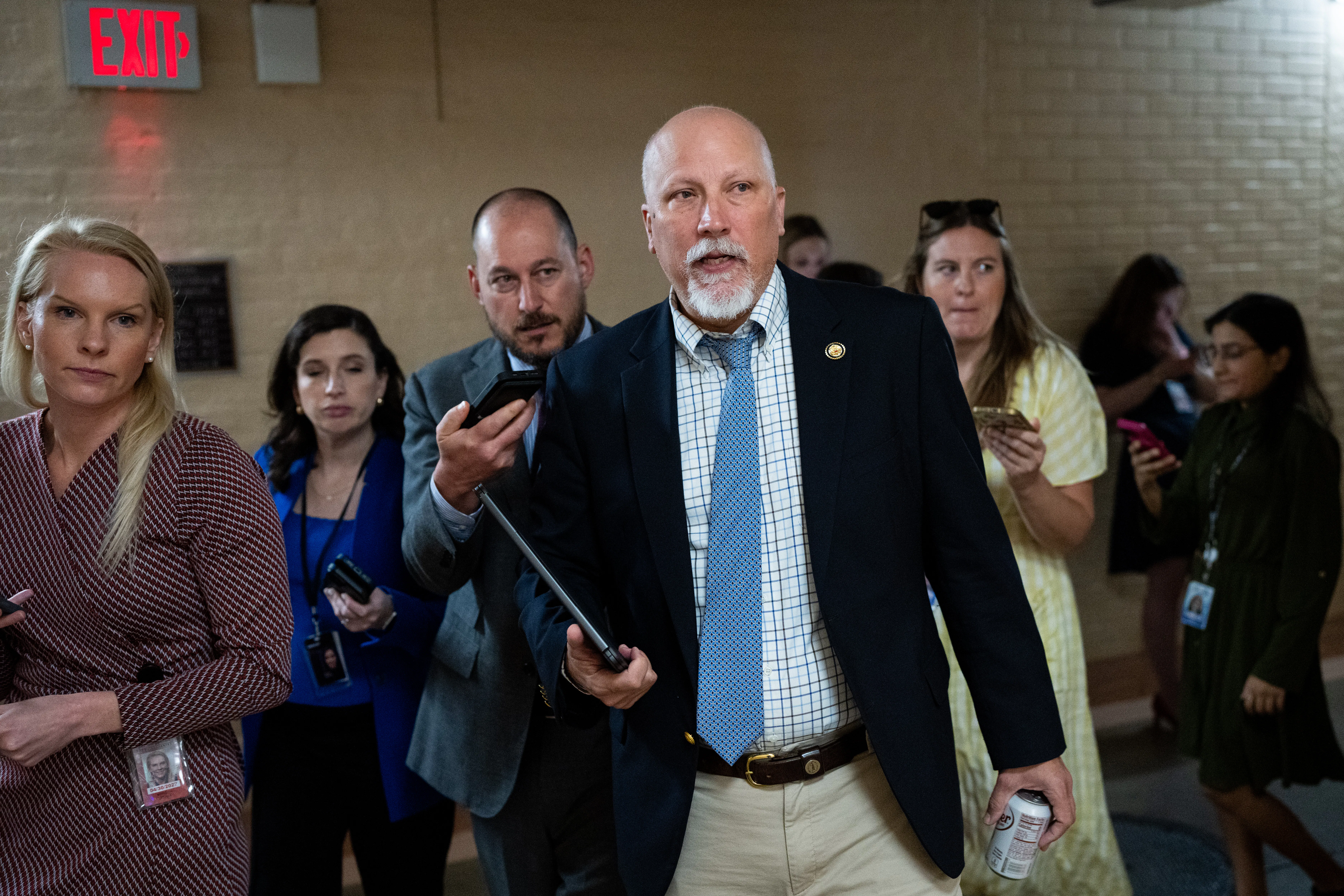 Representative Chip Roy he walks in the Capitol with a tablet in his hand as reporters trail him.