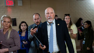 Representative Chip Roy he walks in the Capitol with a tablet in his hand as reporters trail him.