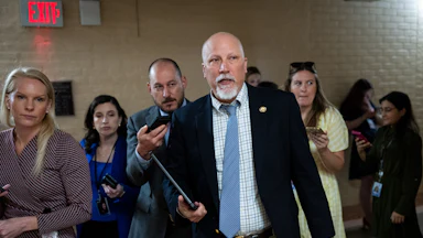 Representative Chip Roy he walks in the Capitol with a tablet in his hand as reporters trail him.