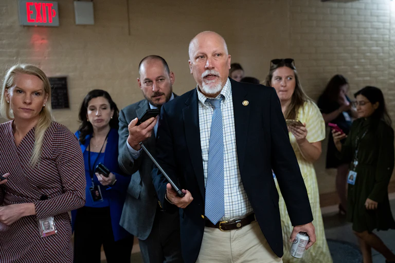Representative Chip Roy he walks in the Capitol with a tablet in his hand as reporters trail him.