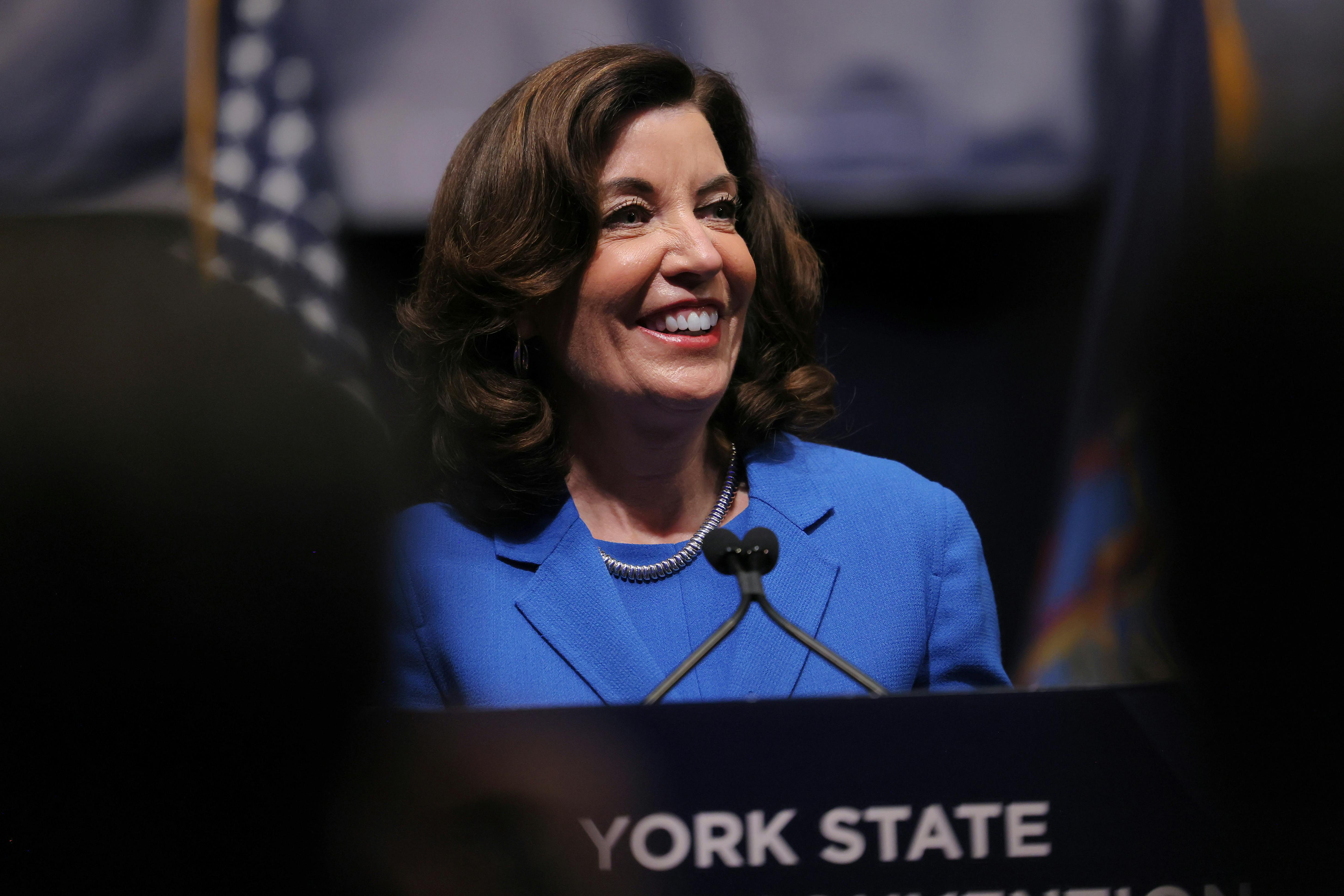 Kathy Hochul smiles while standing at a podium.