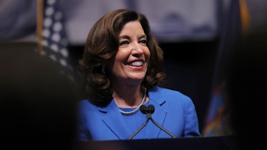 Kathy Hochul smiles while standing at a podium.