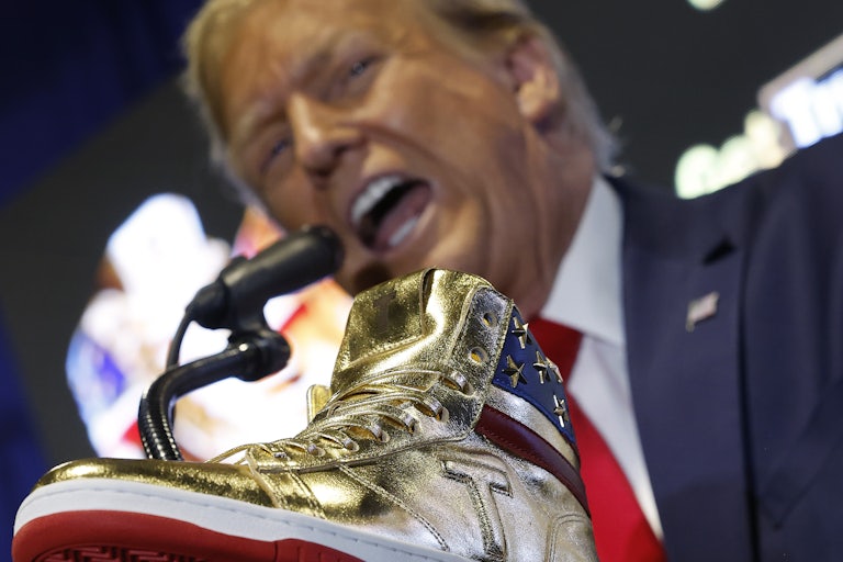 Trump yells in the background with a gold sneaker in the foreground
