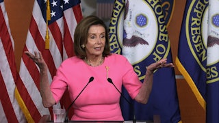 Nancy Pelosi stands behind a lectern shrugging at a press conference on Capitol Hill.