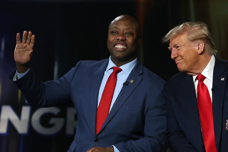 Tim Scott waves as he stands next to Donald Trump