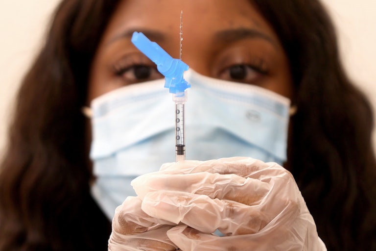 A health care worker holds a syringe and needle.