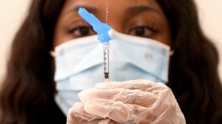 A health care worker holds a syringe and needle.