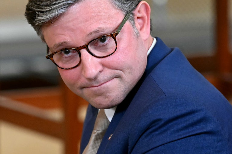 House Speaker Mike Johnson makes a weird face as he bows his head down slightly.