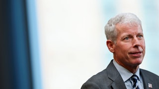 Chris Wright is seen from the shoulders up wearing a suit.