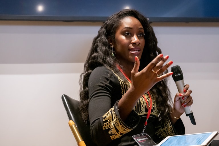 Washington Post columnist Karen Attiah speaks while holding a mic in her hand.