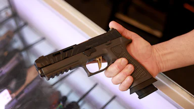 A person holds a SIG Sauer P320 handgun