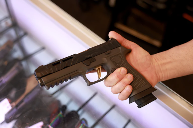 A person holds a SIG Sauer P320 handgun