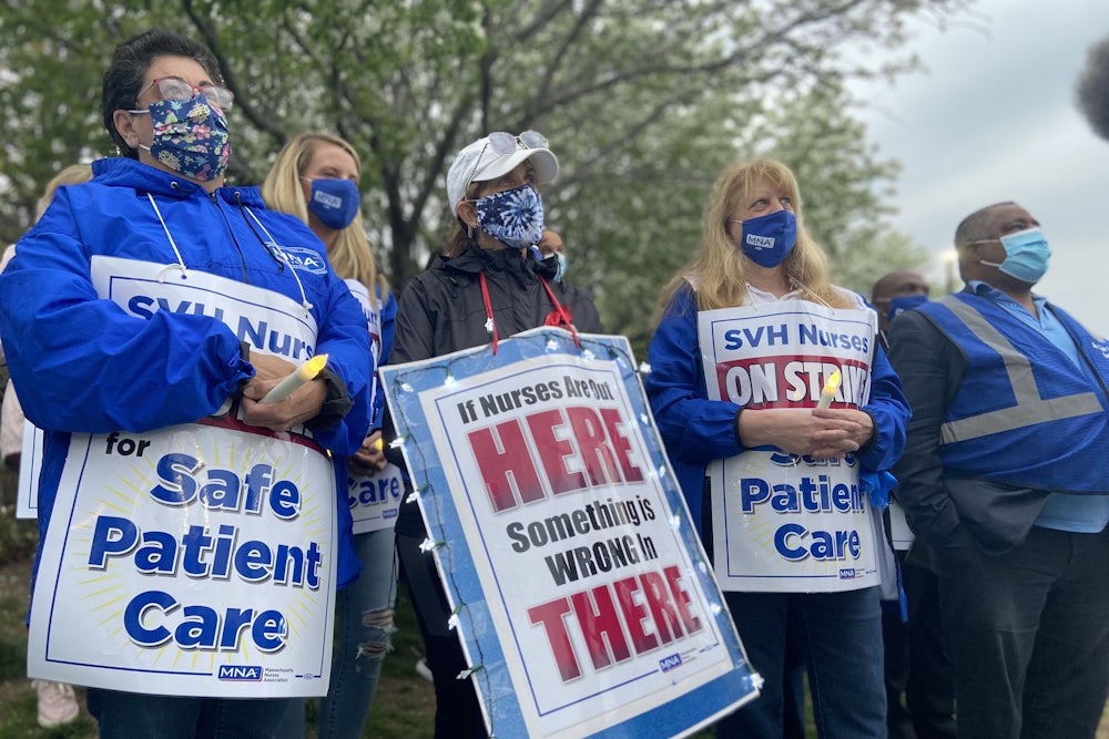 Nurses wear protest signs and hold candles during a strike vigil at Saint Vincent Hospital in Worcester, Massachusetts.