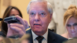 Senator Lindsey Graham stands in a crowd of reporters in the U.S. Capitol