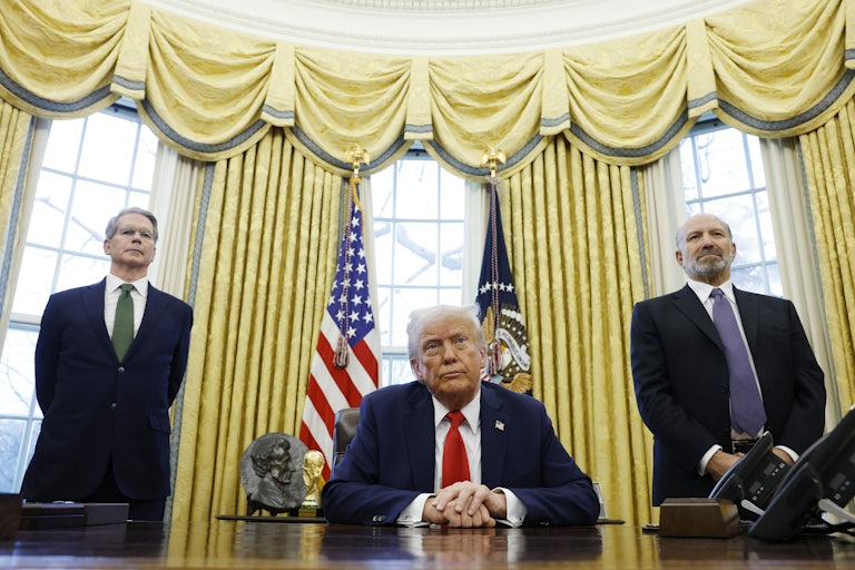 Treasury Secretary Scott Bessent and Commerce Secretary nominee Howard Lutnick stand and flank Trump, who is sitting at his desk in the Oval Office