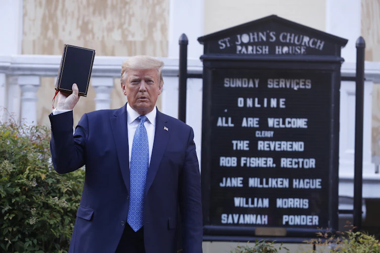 President Donald Trump holds up in his right hand as he stands in front of St. John’s Episcopal Church.
