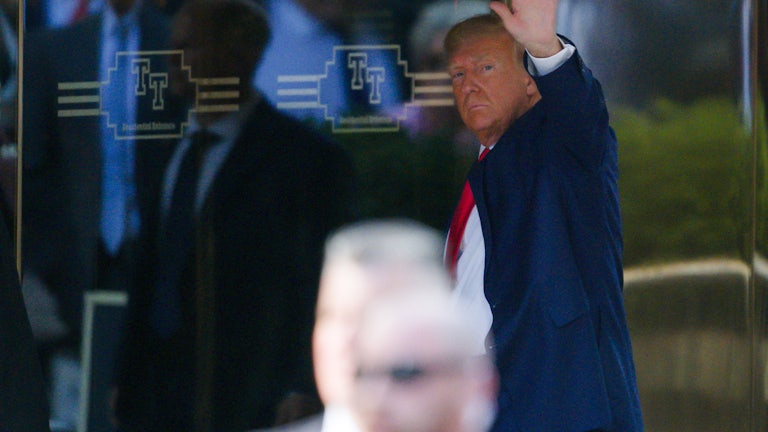 Donald Trump waves as he enters a building.
