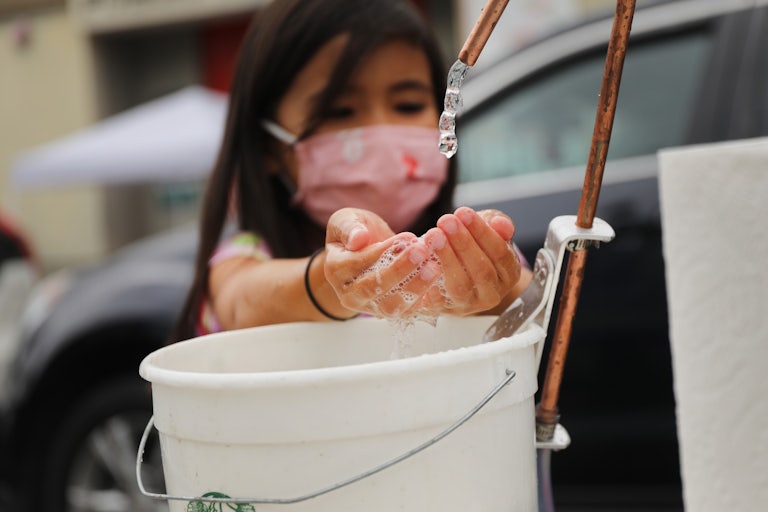 A child washes hands at an outdoor learning demonstration during the pandemic.
