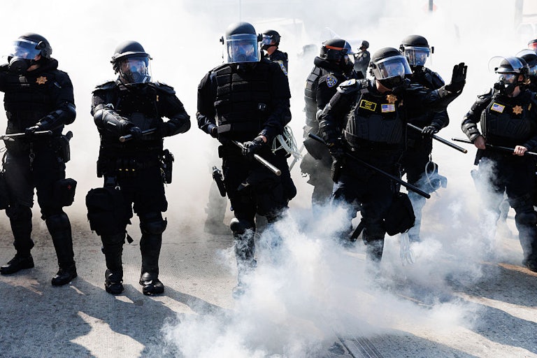 California Highway Patrol using smoke grenades and wearing face shields.