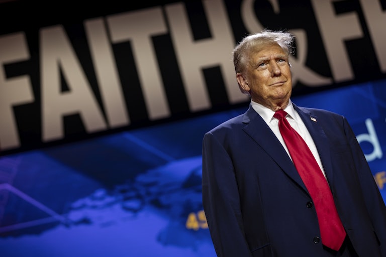 Donald Trump stands and smiles weirdly