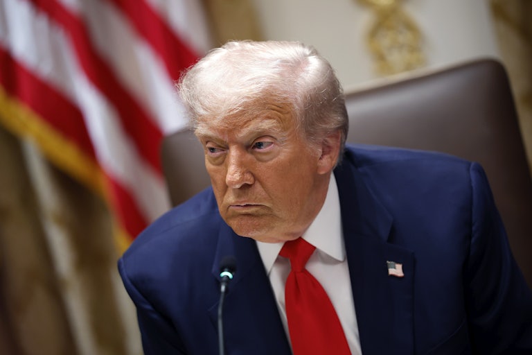 Donald Trump leans over as he's seated