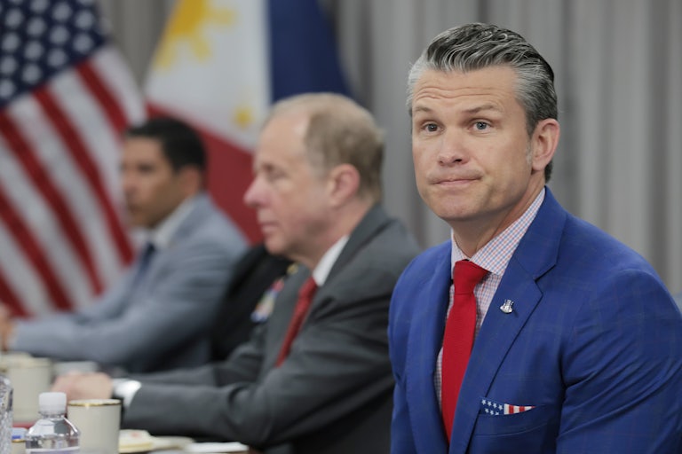 Defense Secretary Pete Hegseth sits at a conference table with two other men next to him.