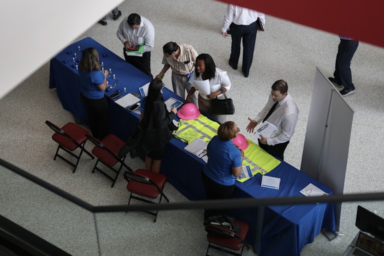 People at a job fair congregate around a table.