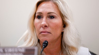 Representative Marjorie Taylor Greene looks grim while sitting in a House hearing.
