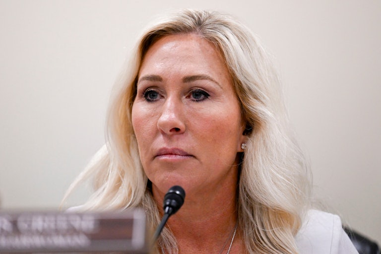 Representative Marjorie Taylor Greene looks grim while sitting in a House hearing.