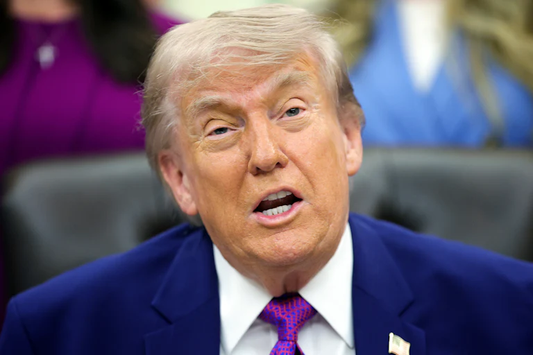 Donald Trump speaks while sitting at his desk in the Oval Office