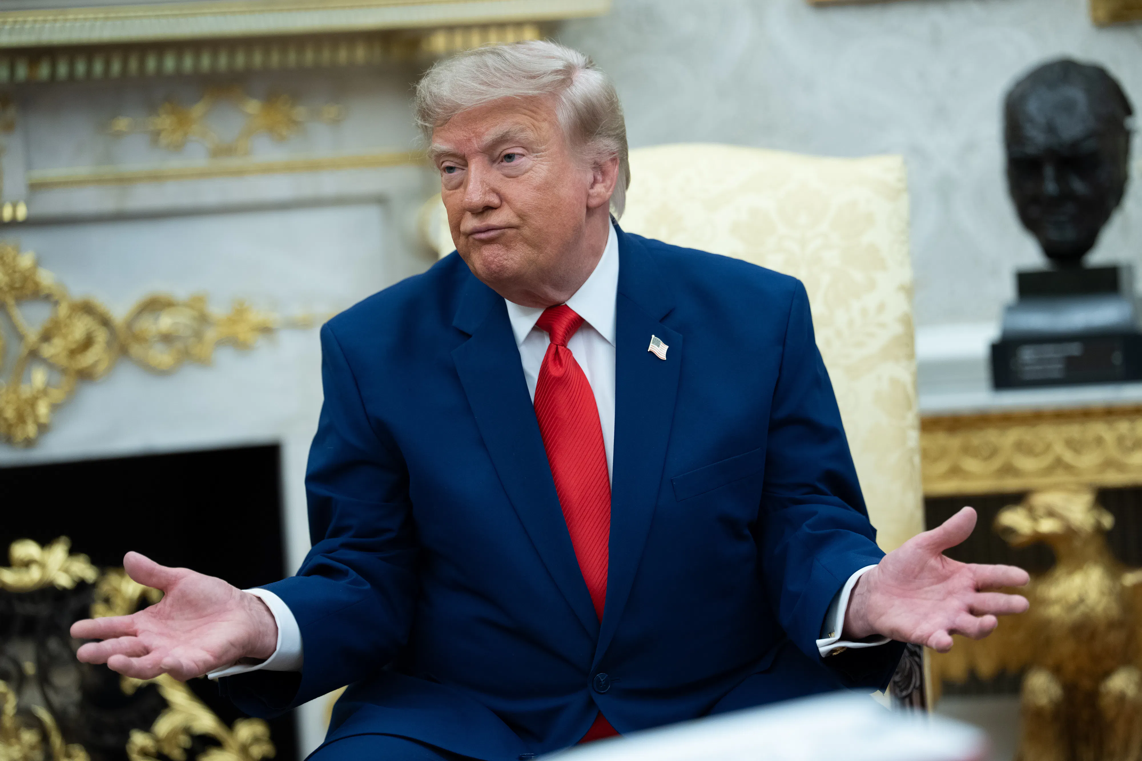 Donald Trump purses his lips and makes a shrugging motion while sitting in the Oval Office.