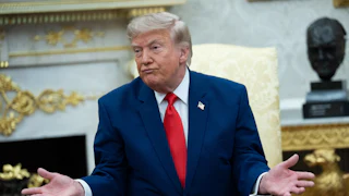 Donald Trump purses his lips and makes a shrugging motion while sitting in the Oval Office.