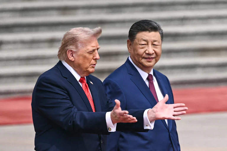 Trump holds out his arms as the wind blows back his hair as he stands outside beside Chinese leader Xi Jinping.