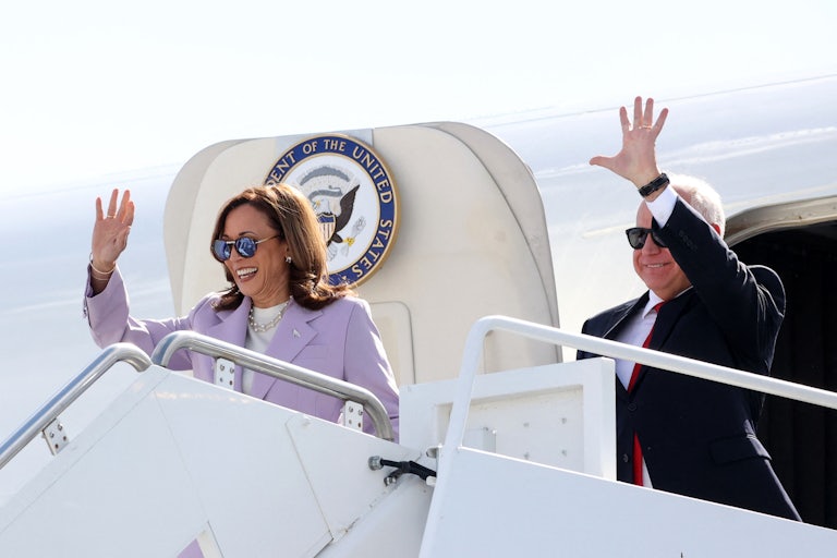 Kamala Harris and Tim Walz wave as they get off the Air Force Two plane