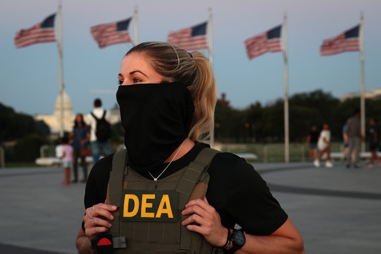 A DEA agent wears a face mask as she stands outside the Washington Monument.