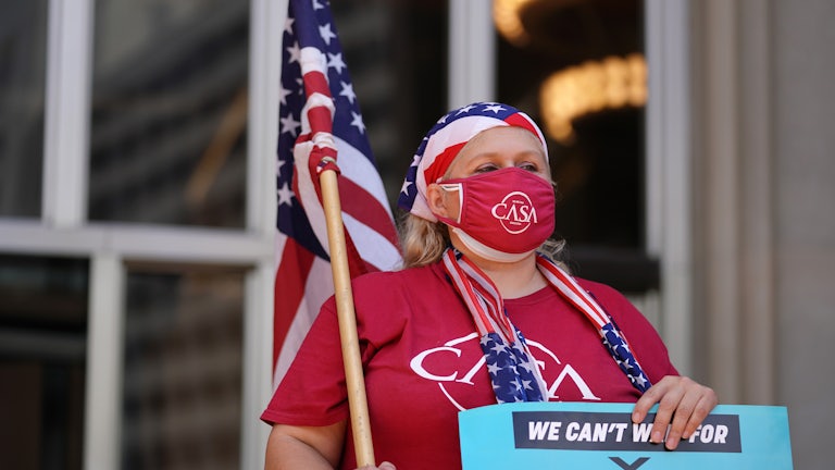 A demonstrator draped in American flag iconography holds a "climate justice" sign.